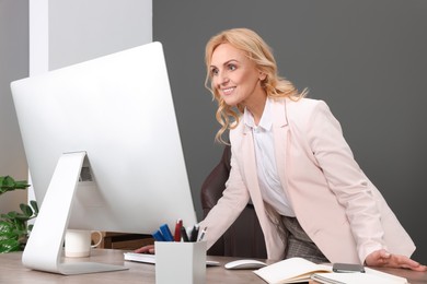 Photo of Happy lady boss working on computer in office. Successful businesswoman