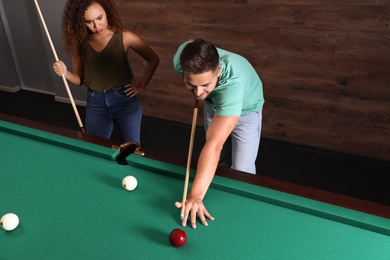 Young man and woman playing billiard indoors, above view