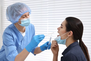 Photo of Laboratory testing. Doctor taking sample from patient's mouth with cotton swab in hospital