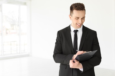 Photo of Male real estate agent with clipboard indoors