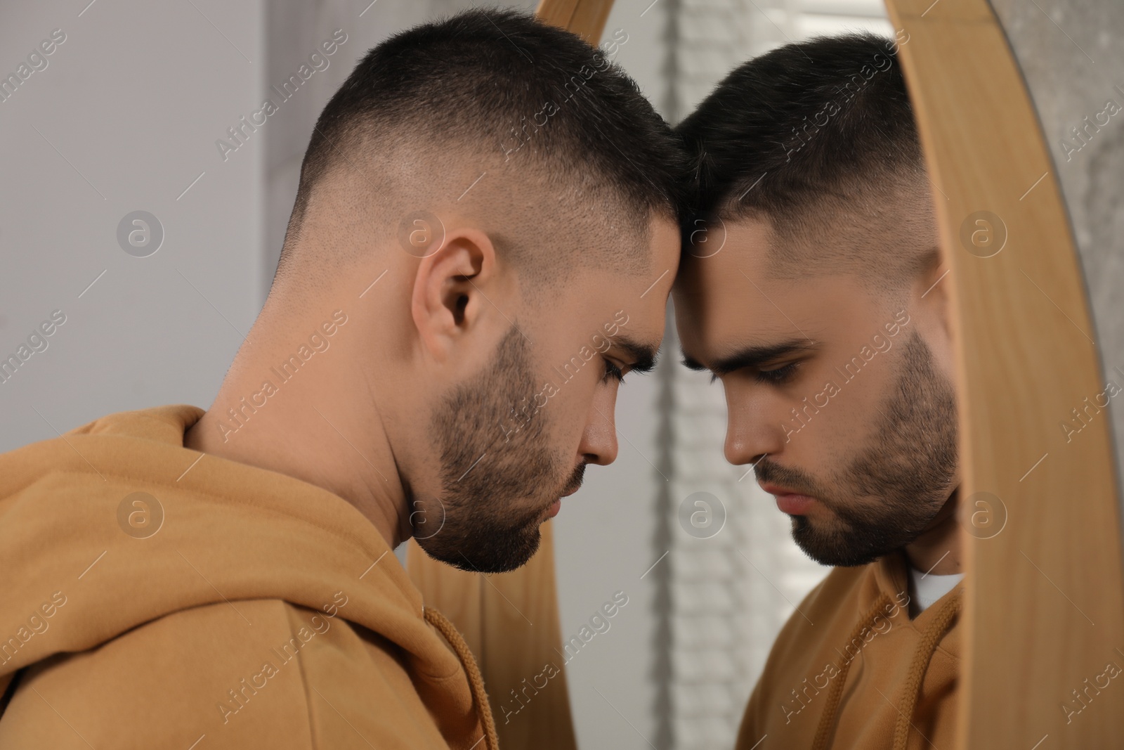 Photo of Sad young man near mirror at home