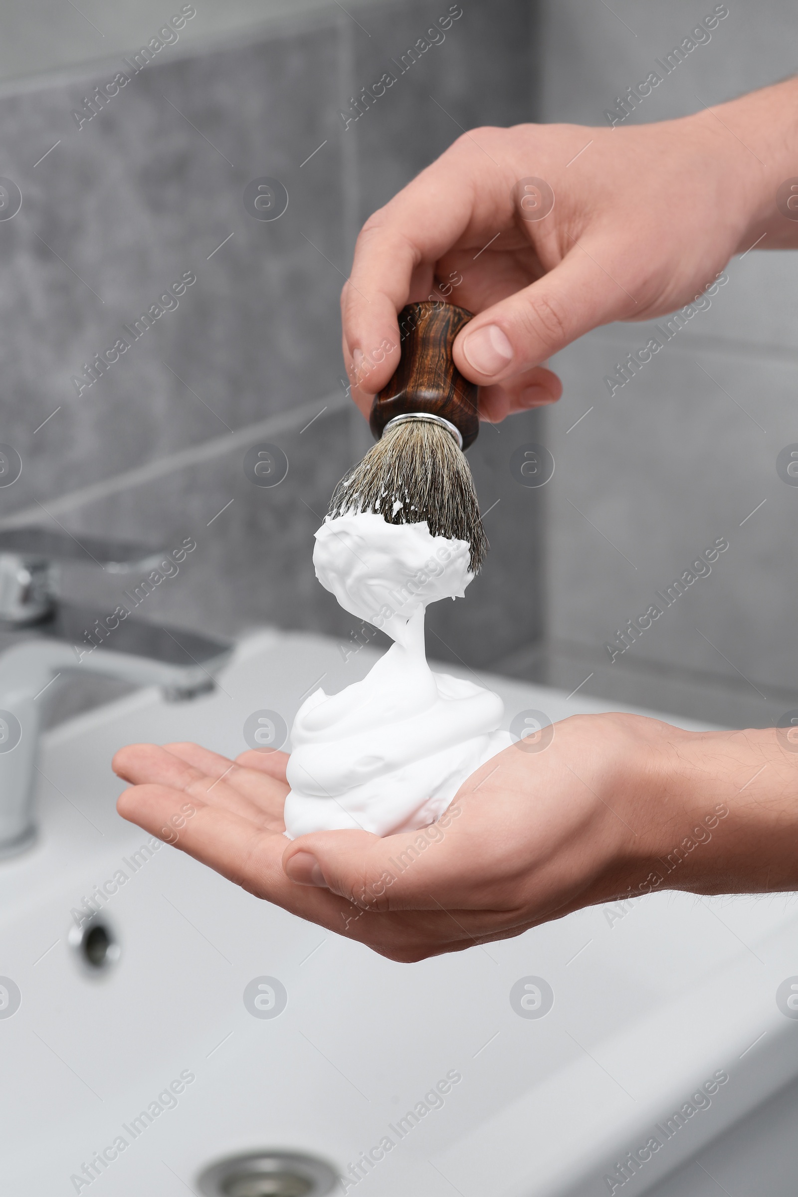 Photo of Man applying shaving foam onto brush in bathroom, closeup