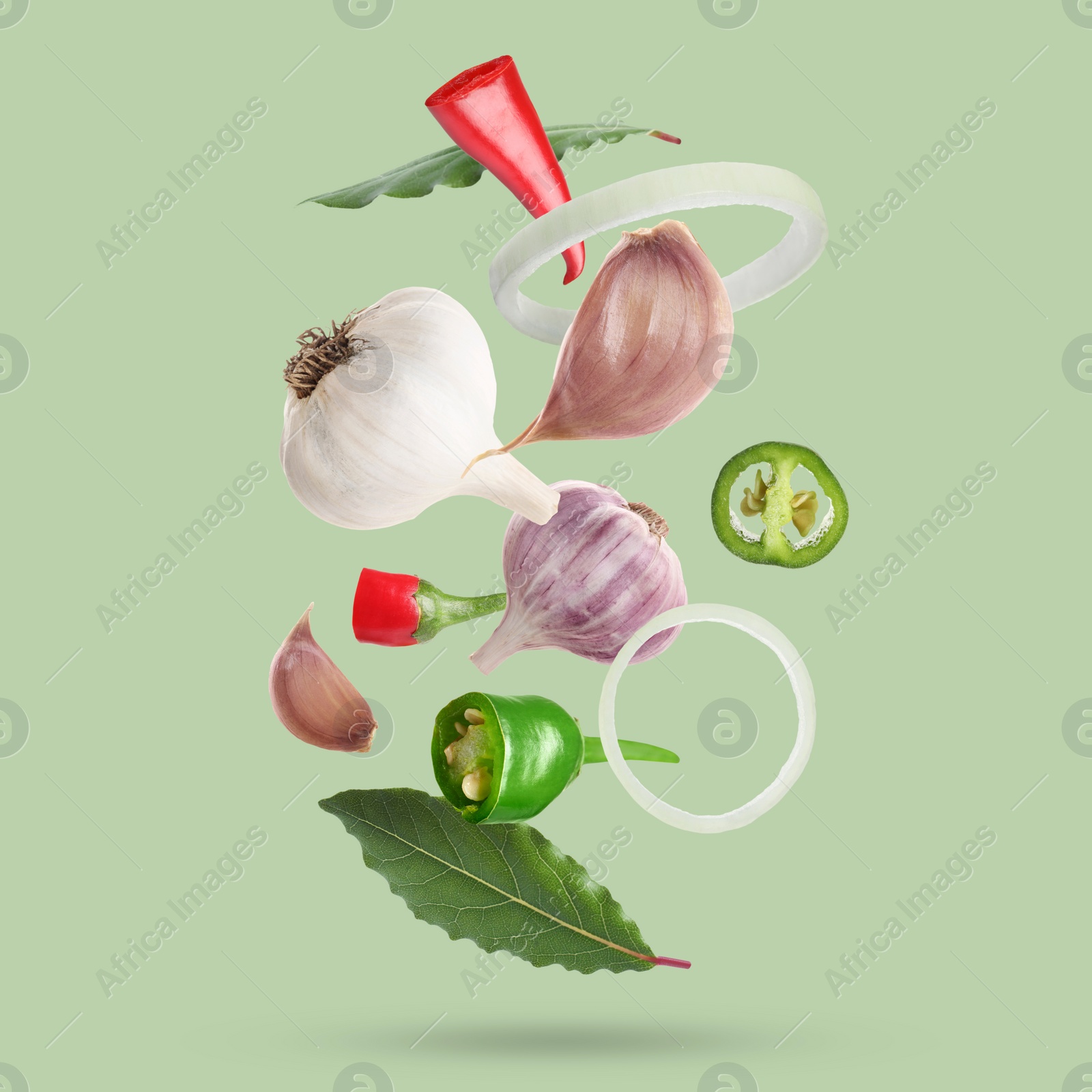 Image of Different spices falling on light green background