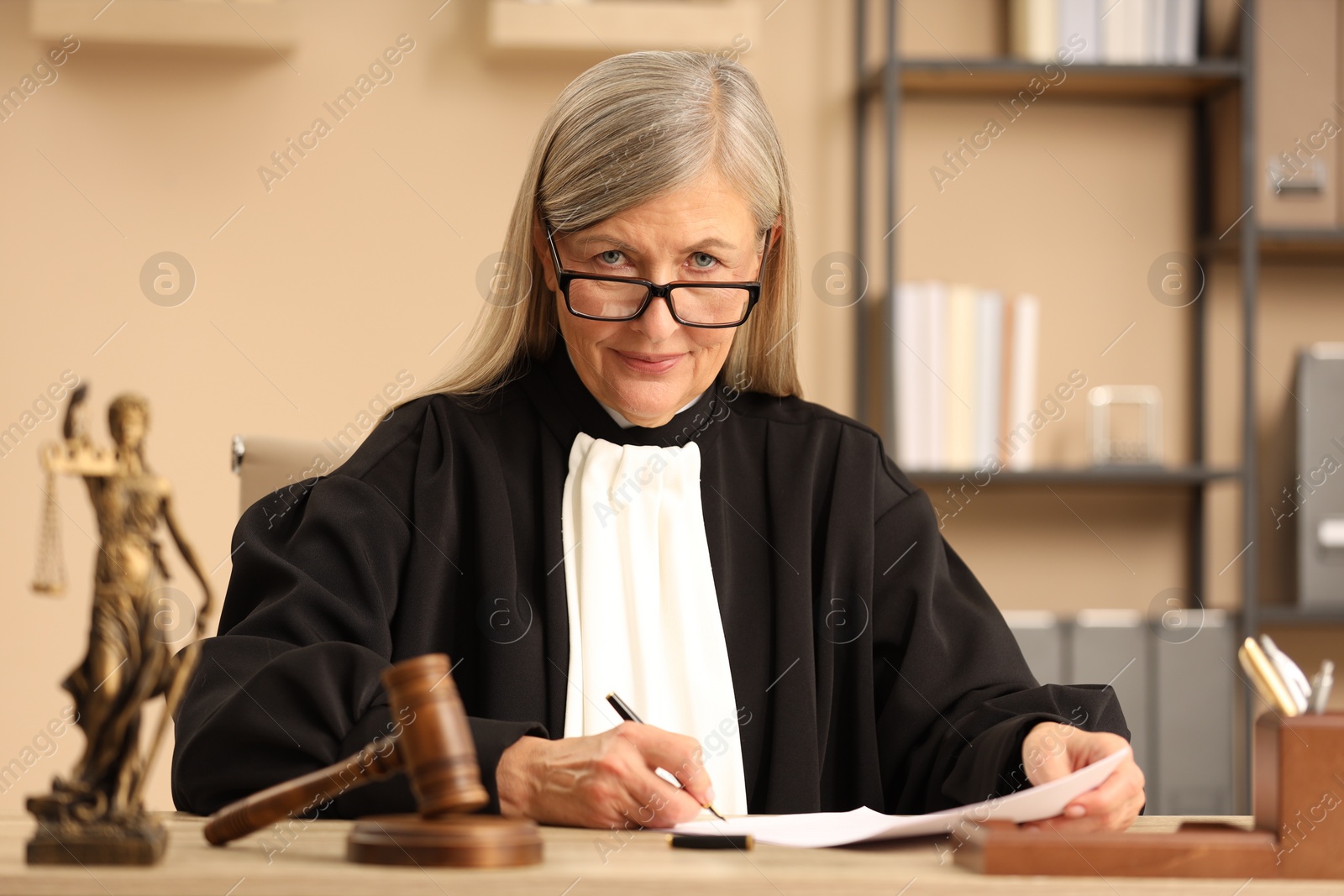 Photo of Judge in court dress working at table indoors