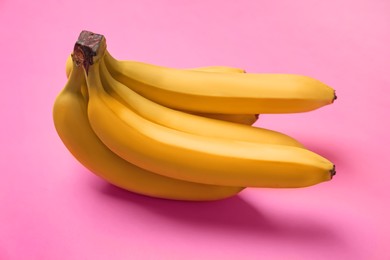 Photo of Bunch of ripe yellow bananas on pink background, closeup