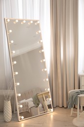 Photo of Large mirror with light bulbs near window in room. Interior design