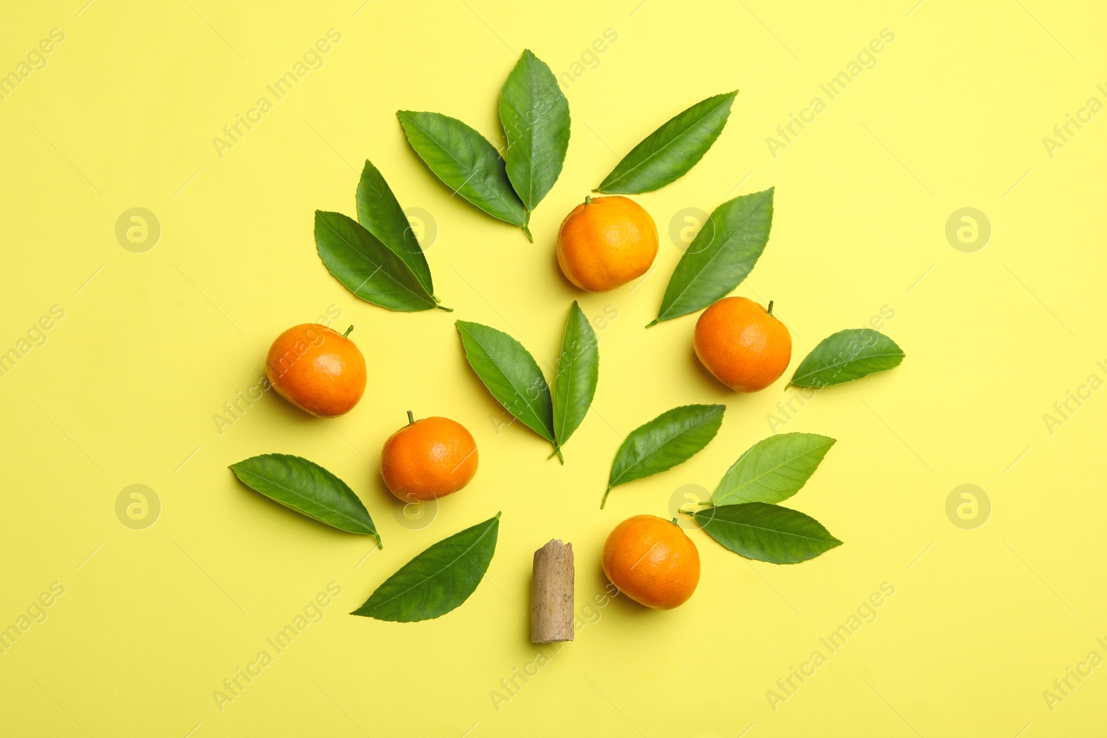 Photo of Flat lay composition with fresh green citrus leaves and tangerines on yellow background