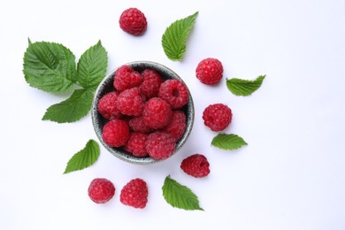 Photo of Tasty ripe raspberries and green leaves on white background, flat lay