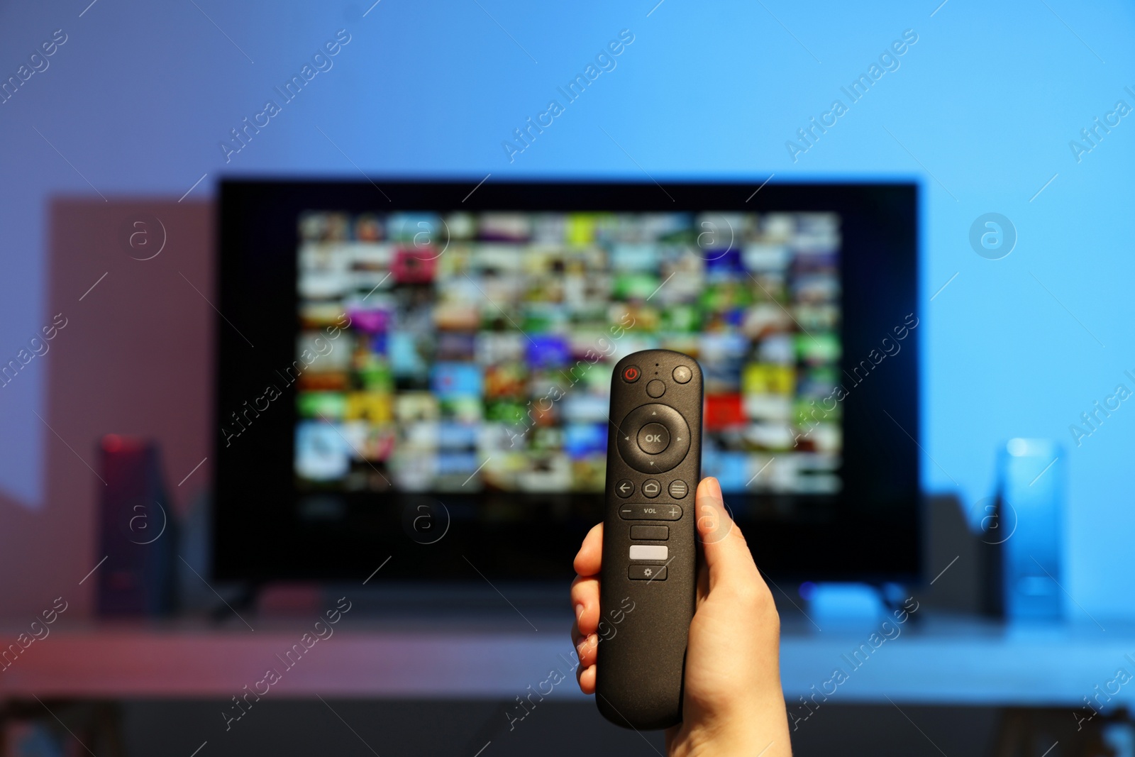 Photo of Woman switching channels on TV set with remote control at home, closeup