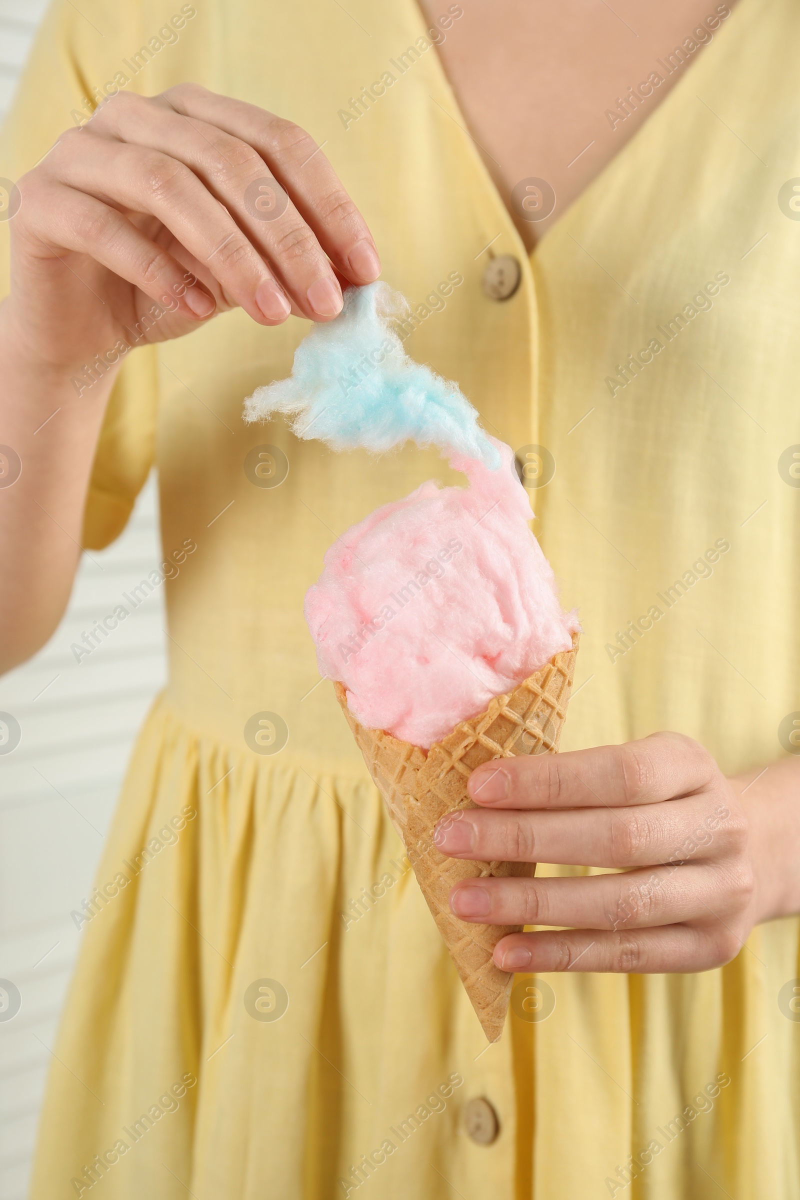 Photo of Woman with waffle cone eating cotton candy, closeup