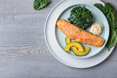 Photo of Tasty salmon with spinach and avocado on grey wooden table, flat lay. Space for text