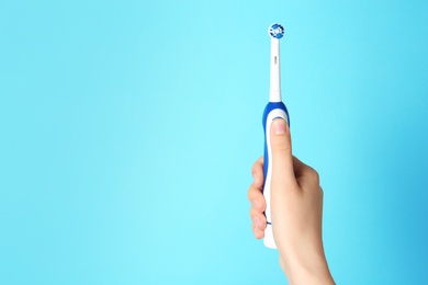 Photo of Woman holding electric toothbrush against color background