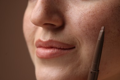 Photo of Beautiful woman with freckle pen on brown background, closeup