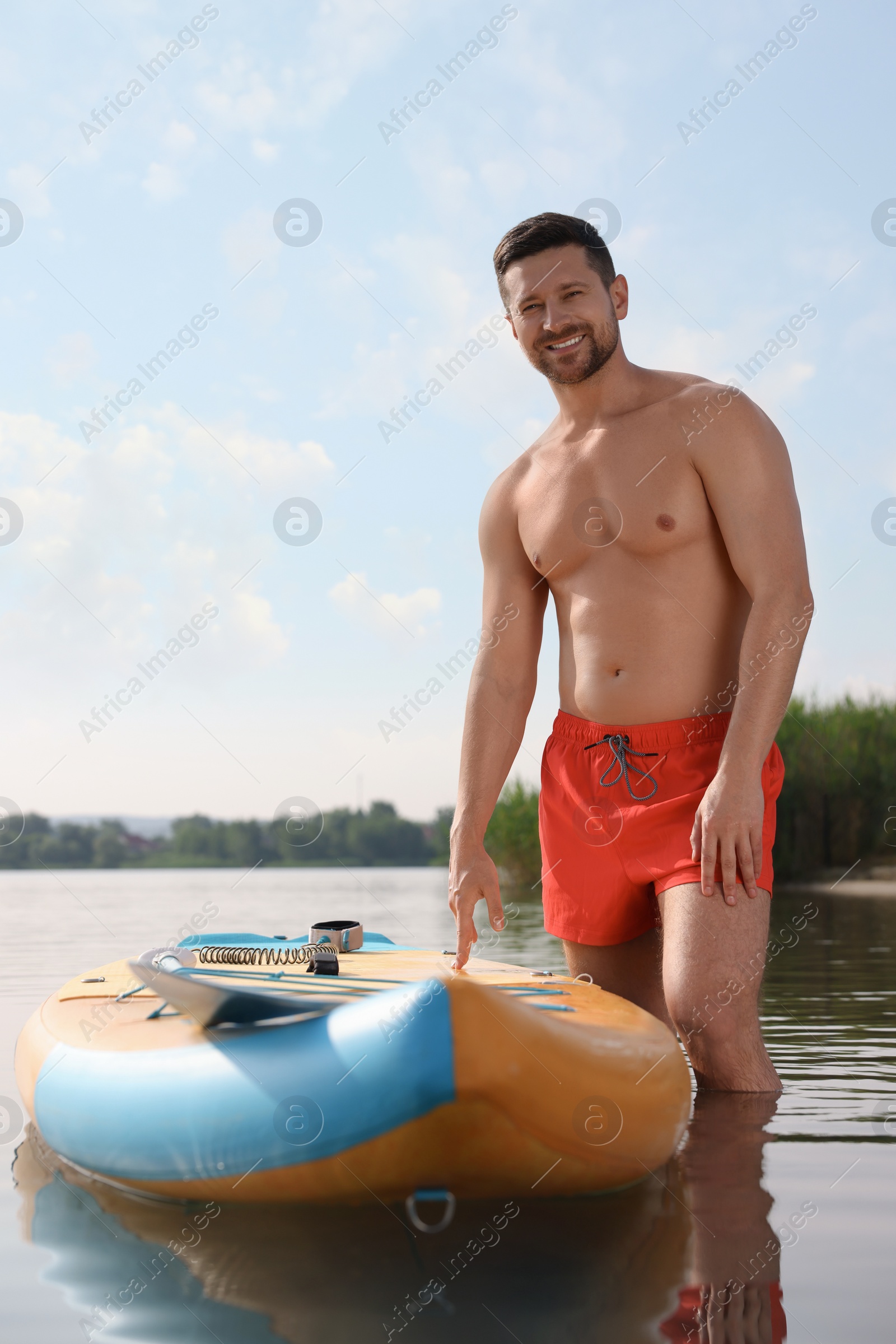 Photo of Man standing near SUP board in water