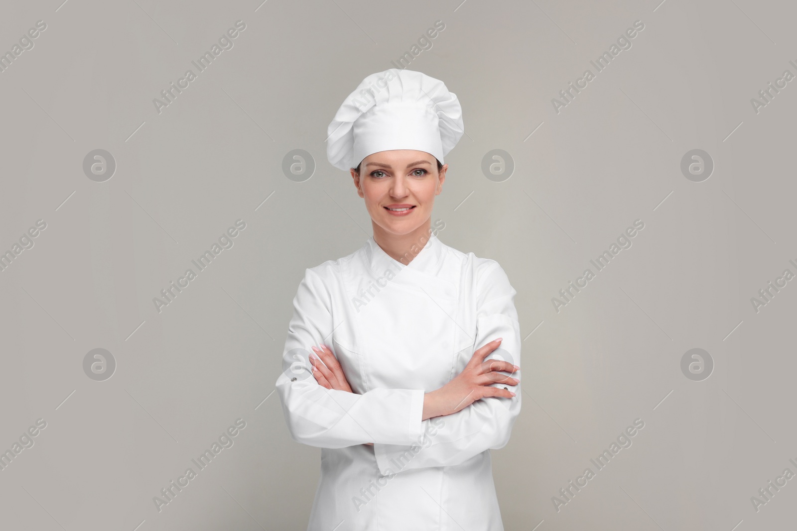 Photo of Happy chef in uniform on grey background