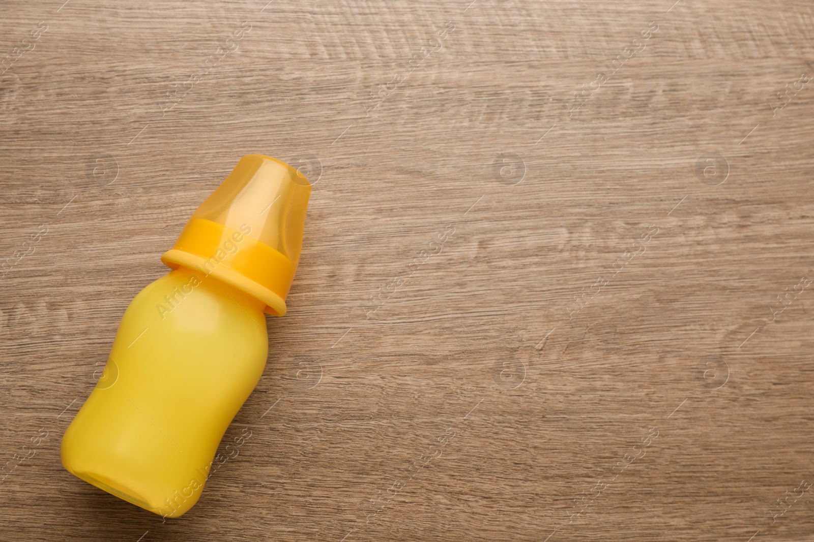 Photo of Feeding bottle with infant formula on wooden table, top view. Space for text