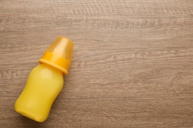 Feeding bottle with infant formula on wooden table, top view. Space for text