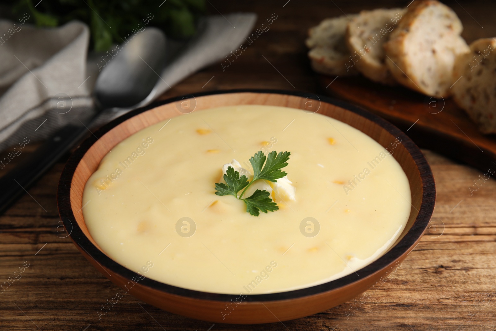 Photo of Delicious corn cream soup served on wooden table