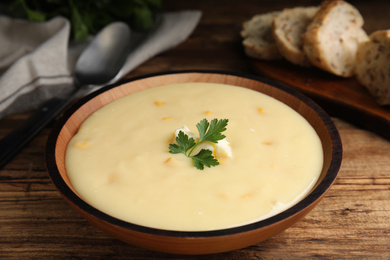 Photo of Delicious corn cream soup served on wooden table