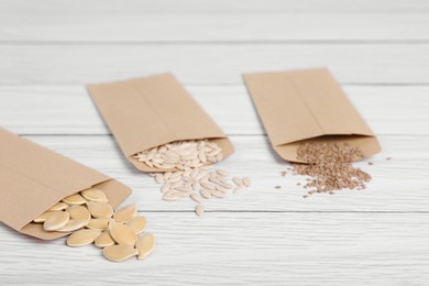 Photo of Many different vegetable seeds on white wooden table, closeup