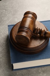 Photo of Wooden gavel, sound block and book on grey textured table, closeup