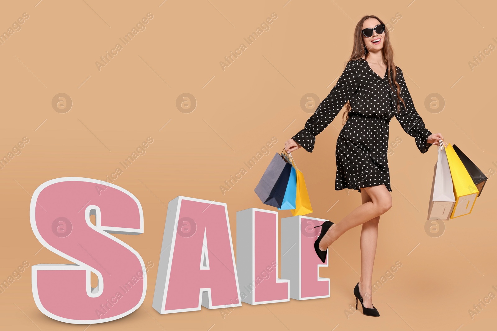 Image of Stylish young woman in sunglasses with shopping bags and word Sale on beige background