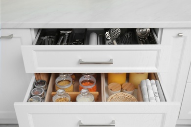 Photo of Open drawers with jars and utensils indoors. Order in kitchen