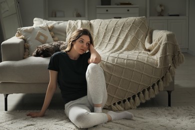 Photo of Sad young woman and her dog at home