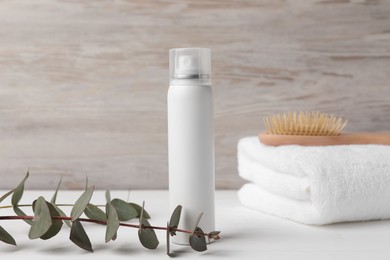 Photo of Dry shampoo spray, towel and eucalyptus on white wooden table