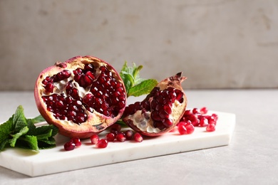 Photo of Ripe pomegranates and seeds on table against light background, space for text