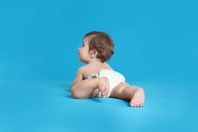 Photo of Cute little baby in diaper on light blue background