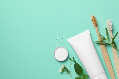 Flat lay composition with bamboo toothbrushes and herbs on turquoise background. Space for text