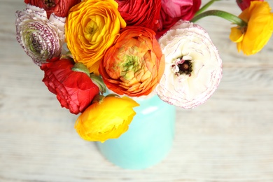 Bouquet of beautiful bright ranunculus flowers in vase on light table, closeup