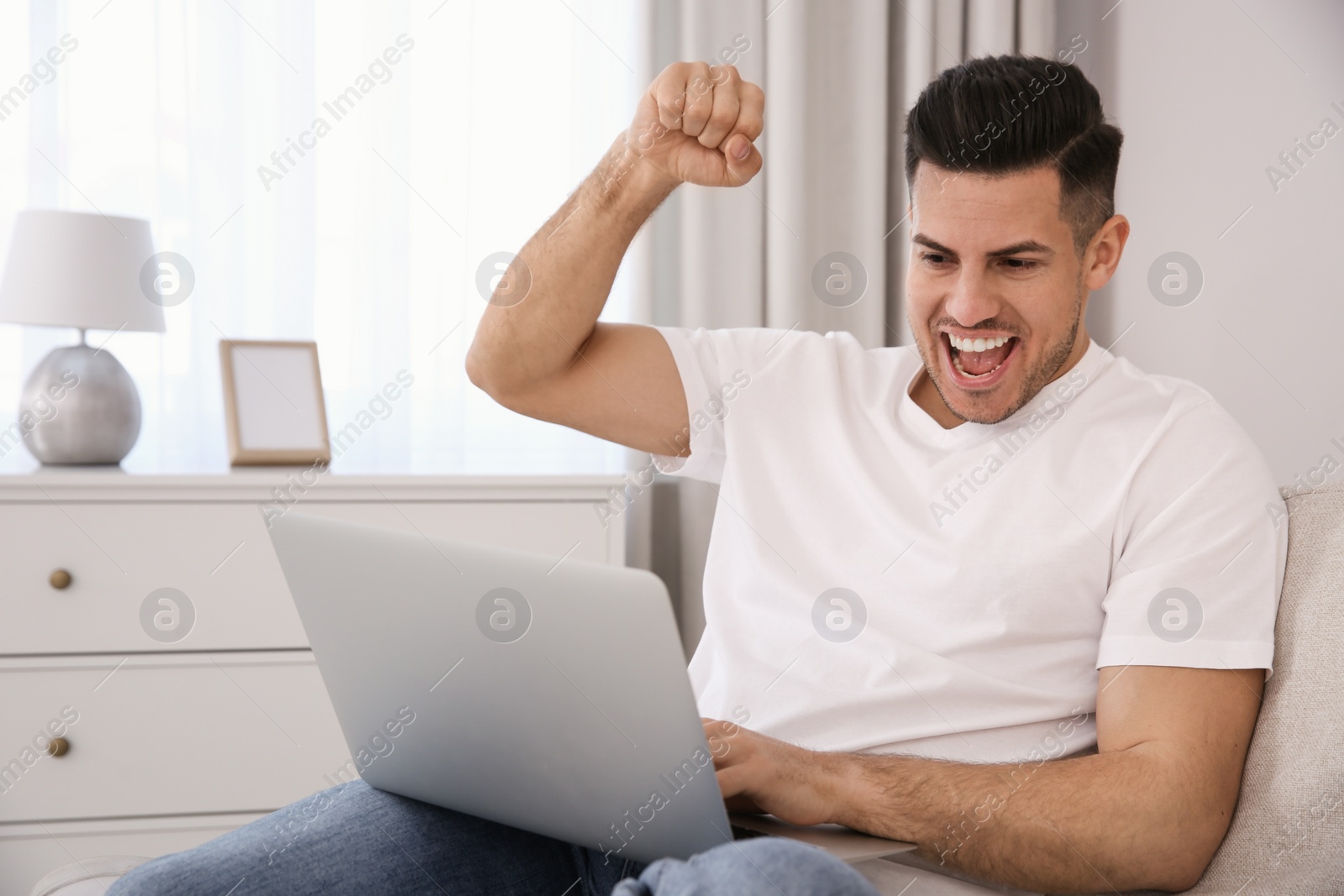 Photo of Emotional man participating in online auction using laptop at home