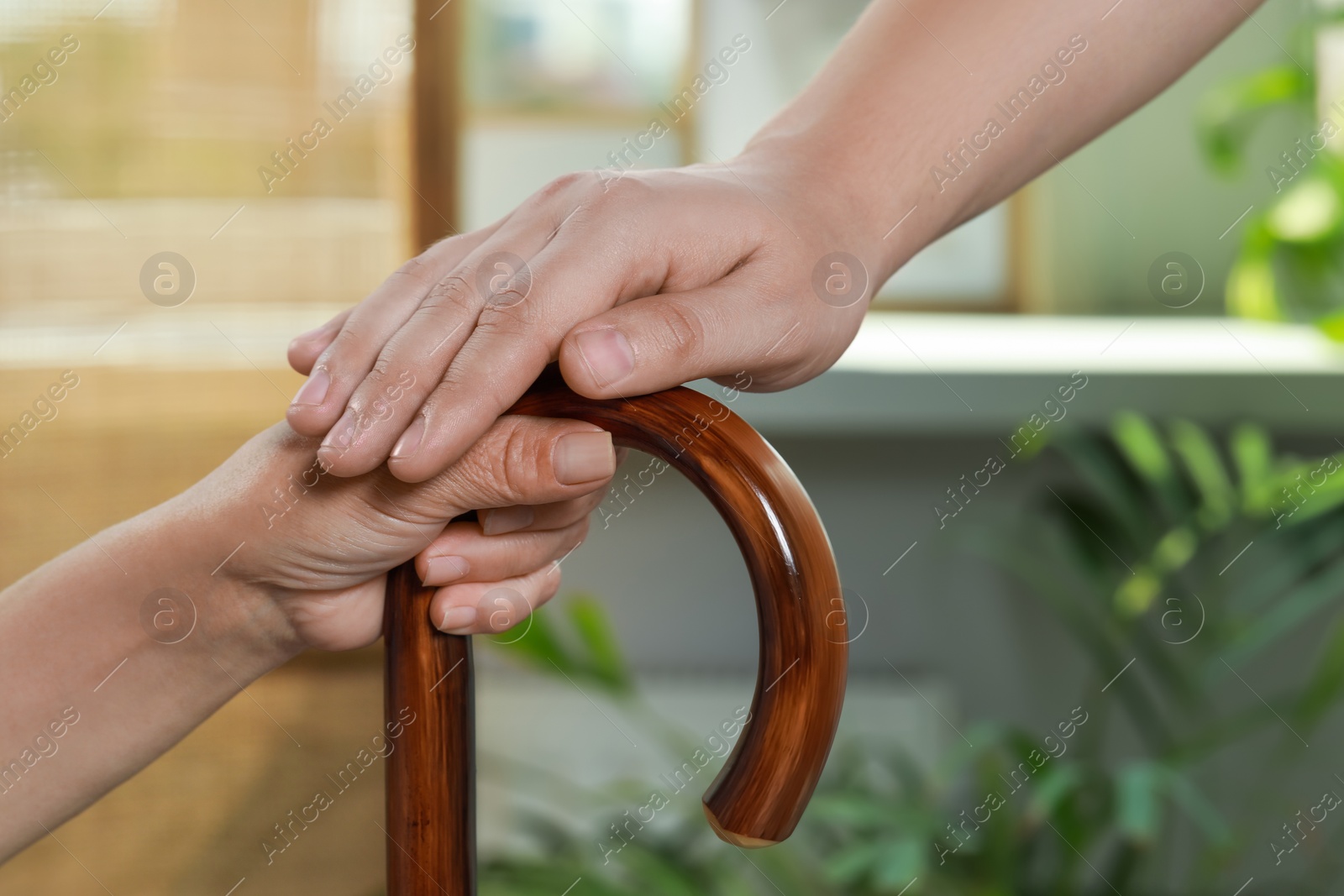 Photo of Caregiver and elderly woman with walking cane at home, closeup