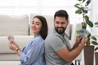 Happy young couple with money at home