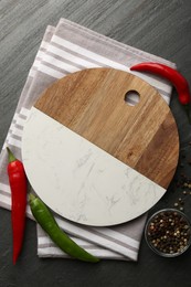 Photo of Cutting board, spices and kitchen towel on dark grey table, flat lay