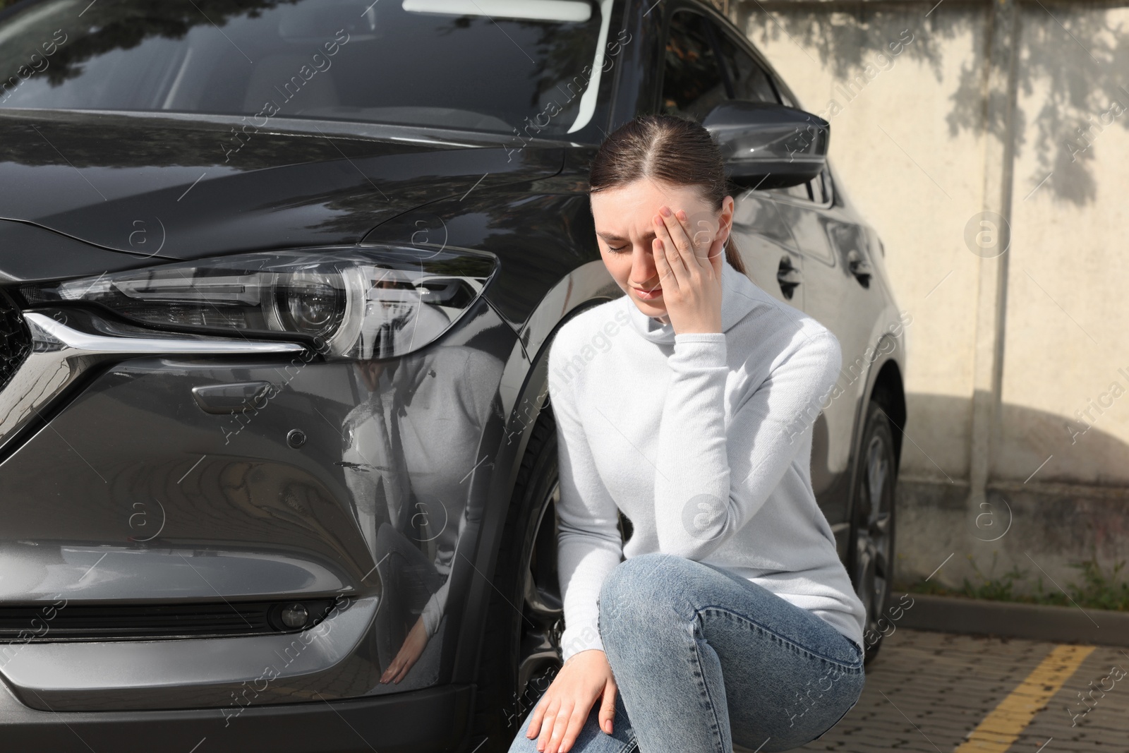 Photo of Stressed woman near car with scratch outdoors