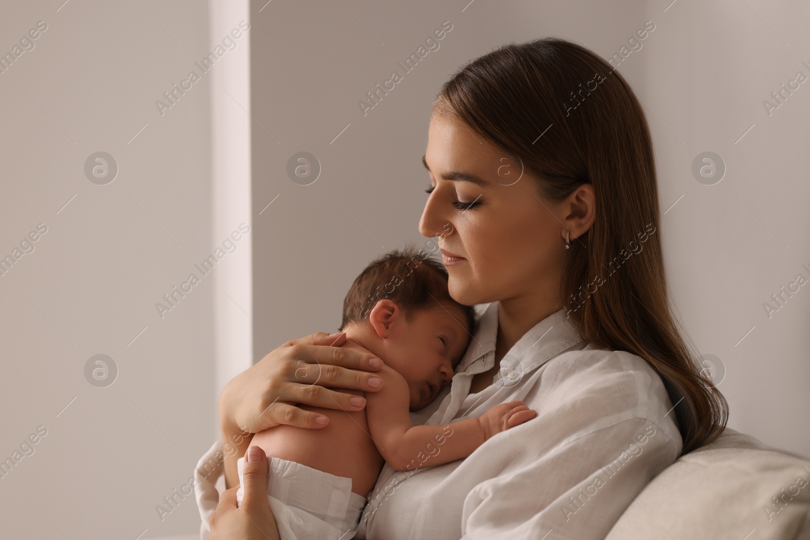 Photo of Mother holding her cute newborn baby indoors