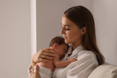 Mother holding her cute newborn baby indoors