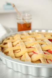 Photo of Raw traditional English apple pie in baking dish on light grey table, closeup