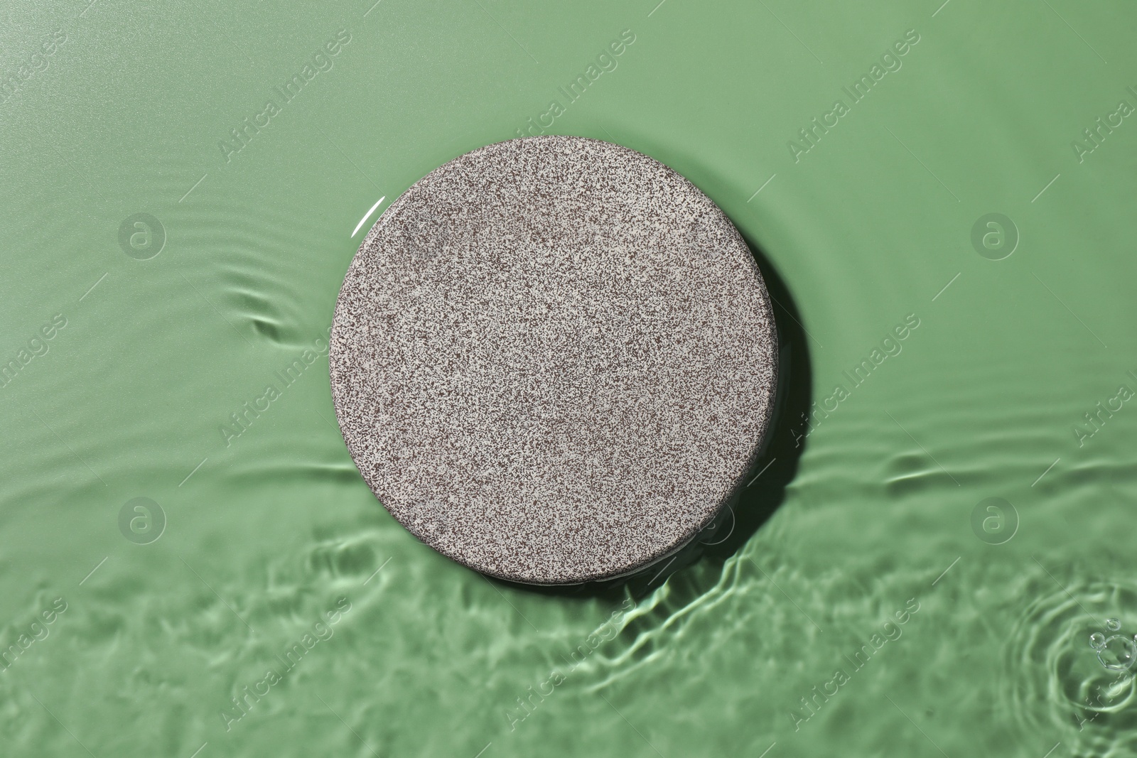 Photo of Presentation for product. Stone podium in water on green background, top view