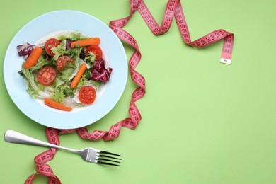 Photo of Plate of fresh vegetable salad, fork and measuring tape on light green background, flat lay with space for text. Healthy diet concept