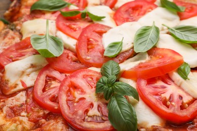 Photo of Delicious Caprese pizza with tomatoes, mozzarella and basil as background, closeup