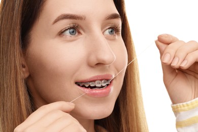 Photo of Smiling woman with braces cleaning teeth using dental floss on white background, closeup