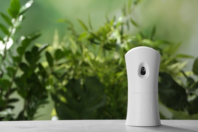 Photo of Automatic air freshener on table against blurred background