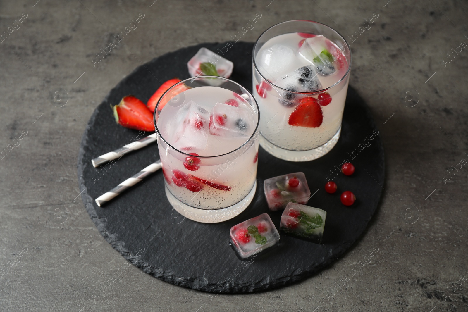 Photo of Glasses of refreshing drink with ice cubes and berries on grey table