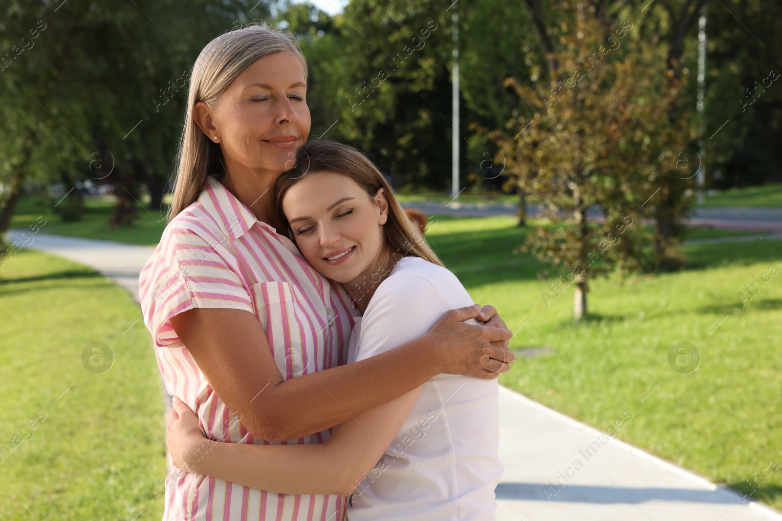 Photo of Family portrait of mother and daughter hugging in park. Space for text