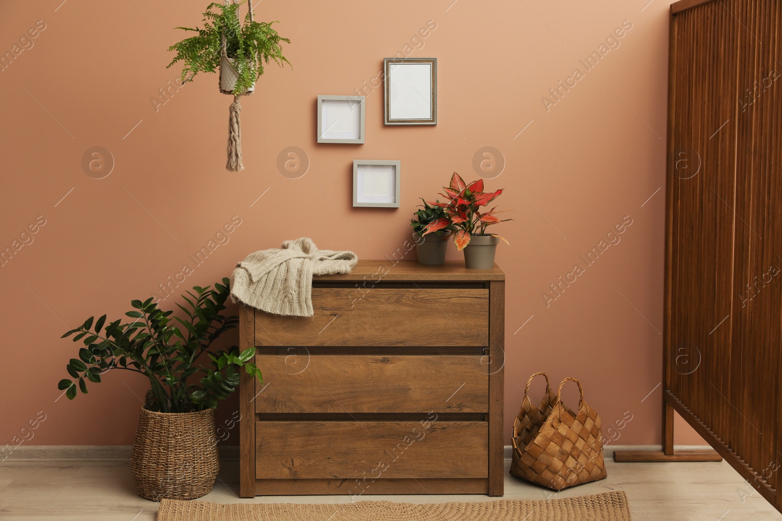 Photo of Wooden chest of drawers near brown wall at home. Interior design