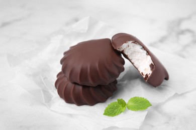 Photo of Delicious chocolate covered marshmallows with mint on white marble table